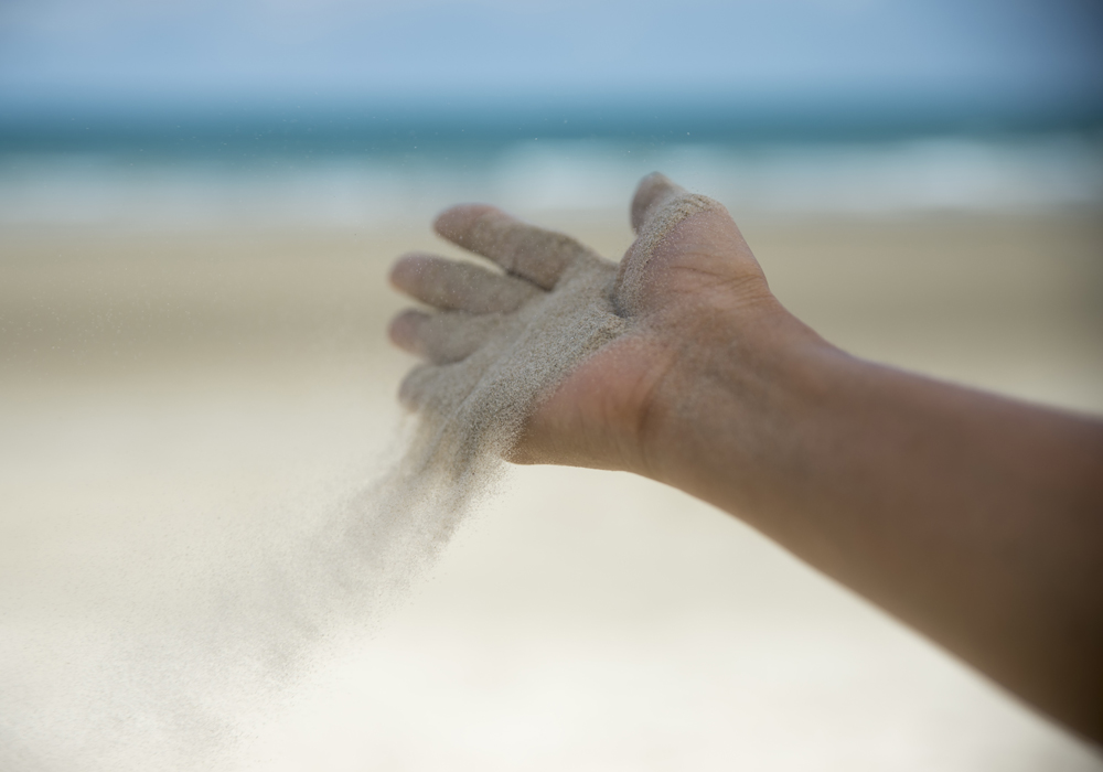 Hand letting go of sand freedom concept